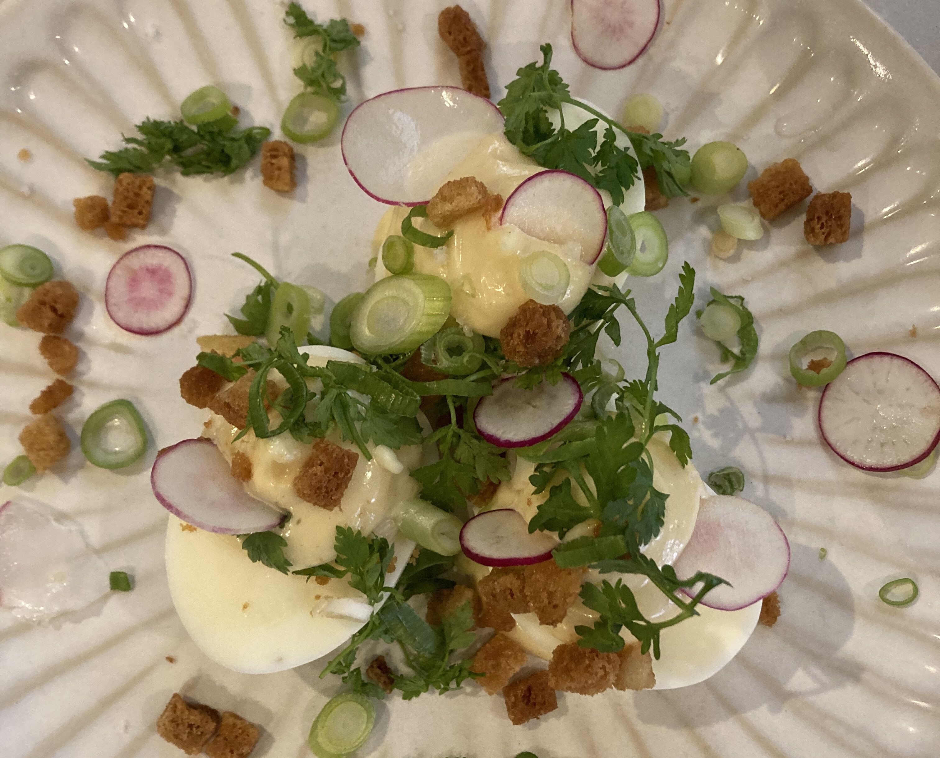 A typical Parisian dish of oeufs mayonnaise richly decorated with croutons and herbs.