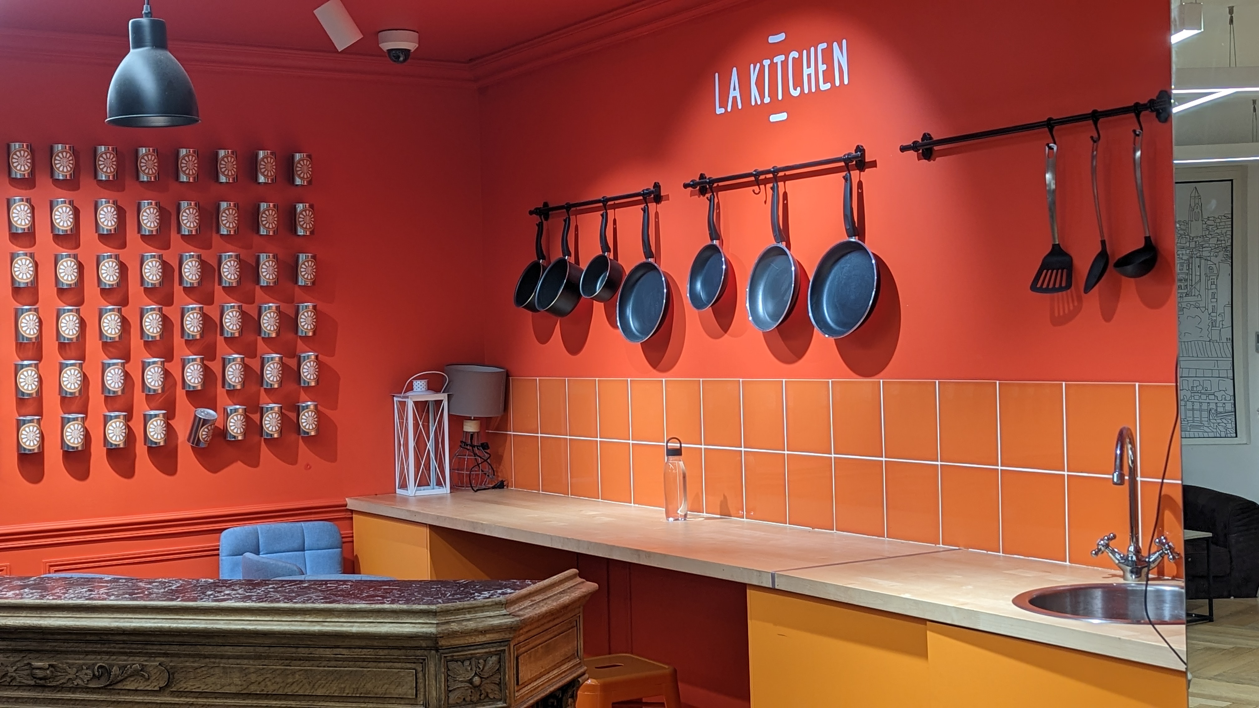 The bright orange and fully equipped kitchen corner of the coworking space.