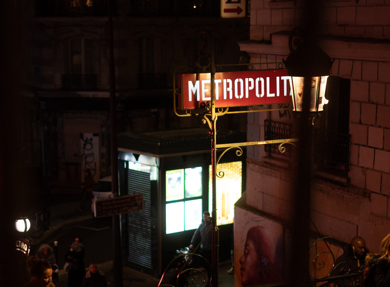 A lit up métropolitain sign by night at Lamarck-Caulaincourt.