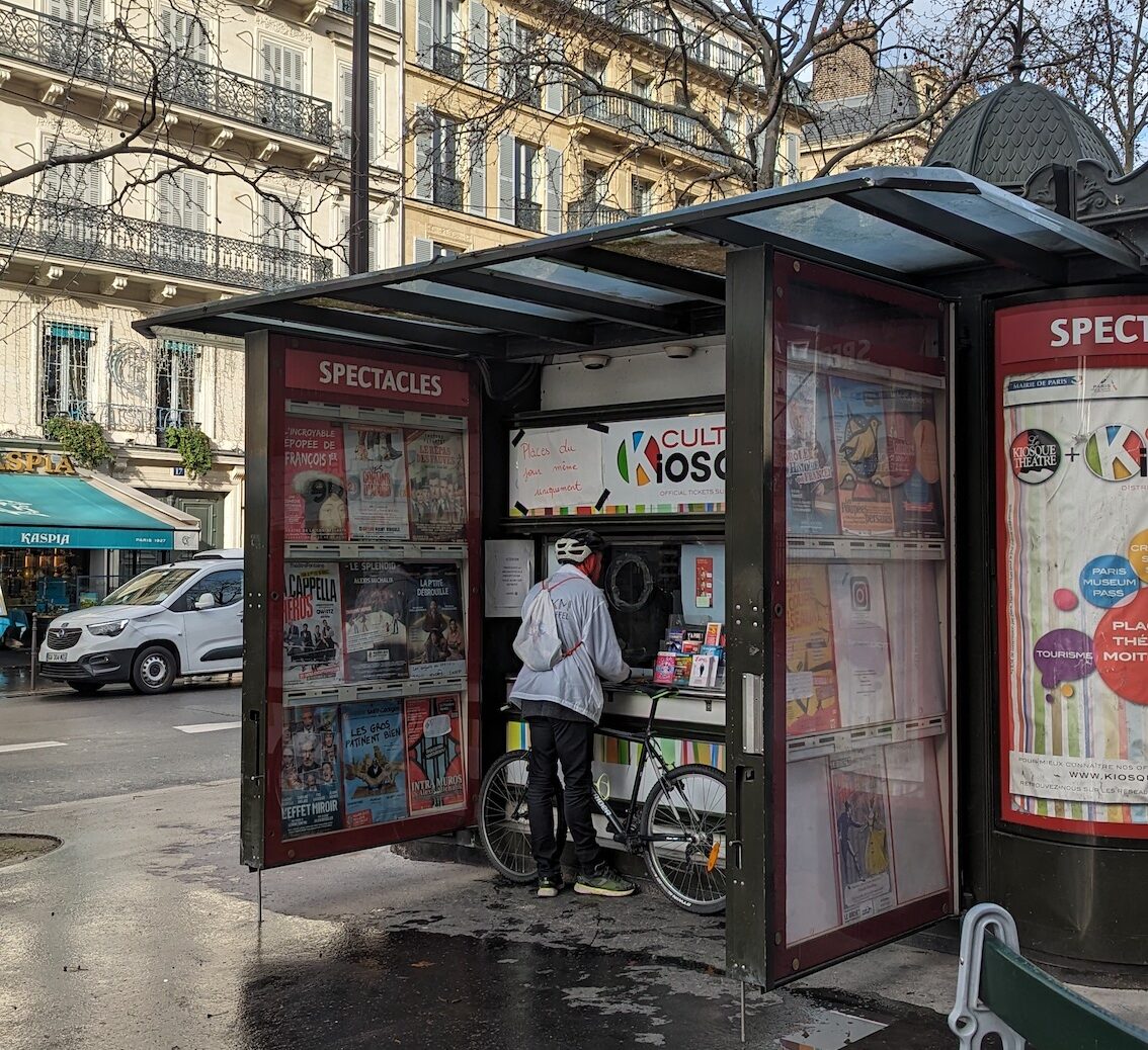 A customer buying discounted tickets to a show at Le Kiosque Culture in Paris.