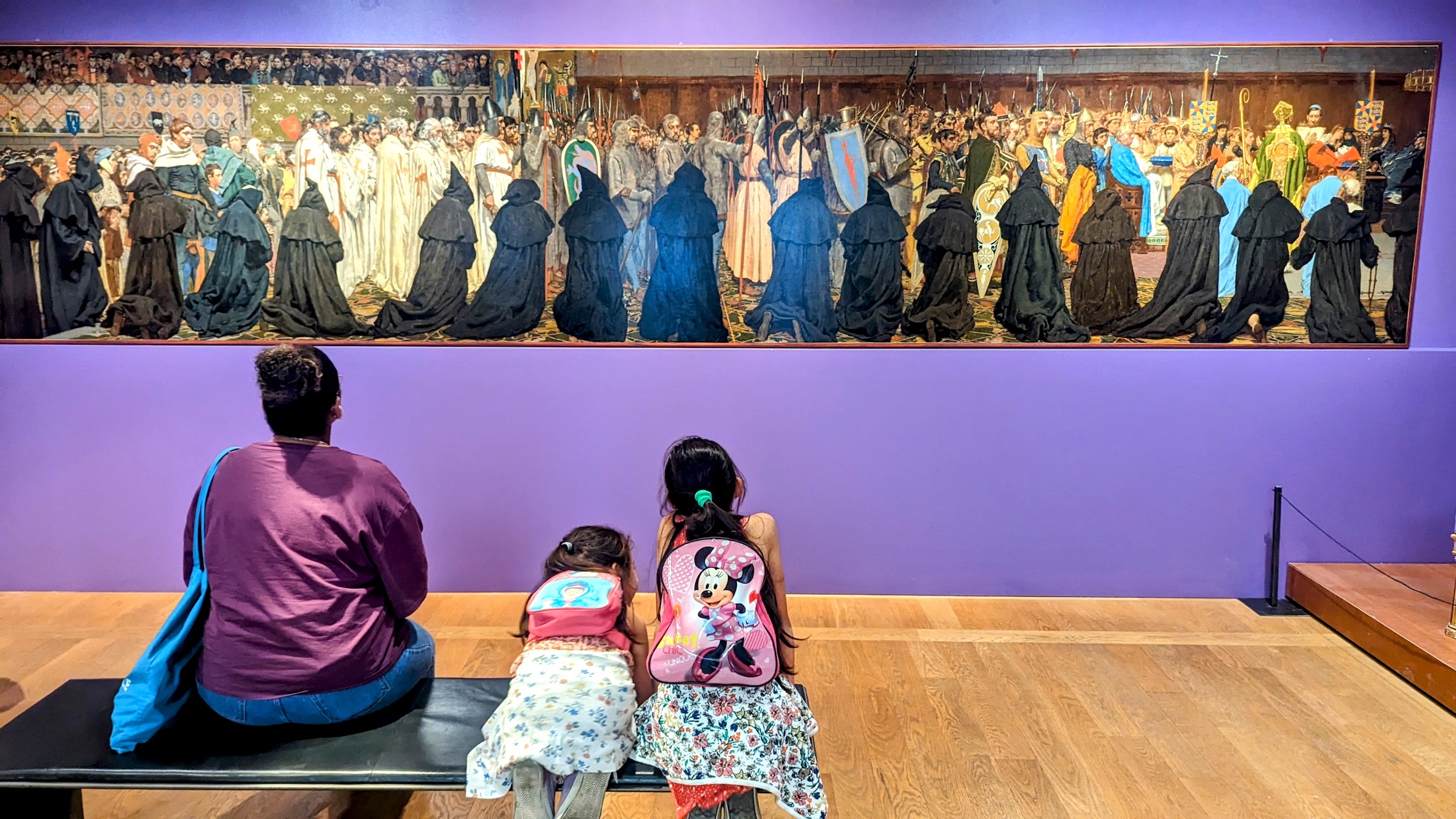 A mother and her two daughters made use of the free entry to the Petit Palais and admire a large painting.