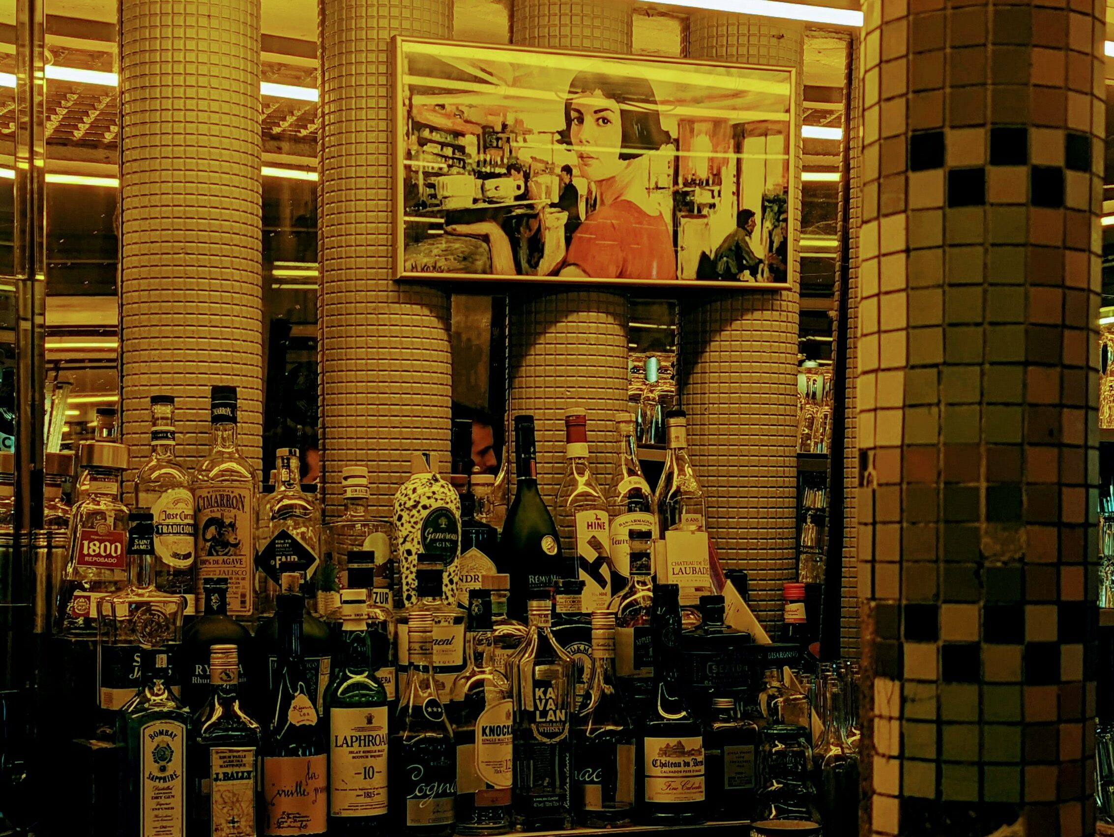 A picture of Amelie Poulain from Jean-Pierre Jeunet's film Le Fabuleux Destin d'Amélie Poulain hangs above the well-stocked bar of Le Moulin à Vent in the 18th arrondissement.