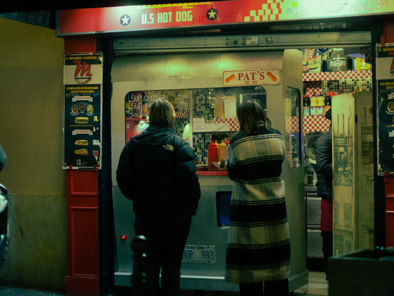 Two tourists, who are staying in the Marais, get a late-night snack from a hotdog vendor in the 4th arrondissement in Paris.