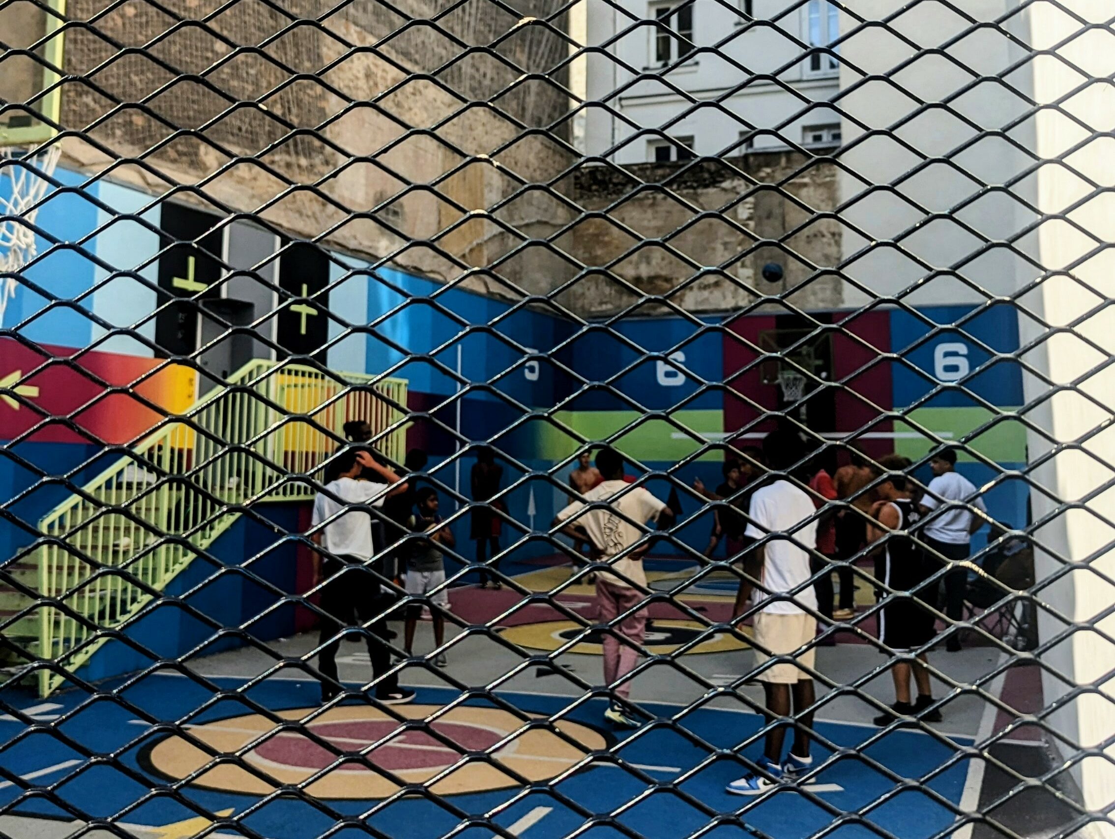 Boys and young men play basketball on the colorful court at Pigalle in Paris.