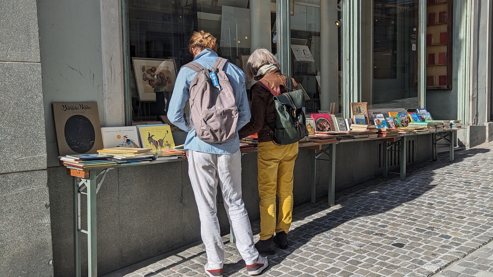 A man and a woman browsing through the display of a book store in the old town of Zurich.