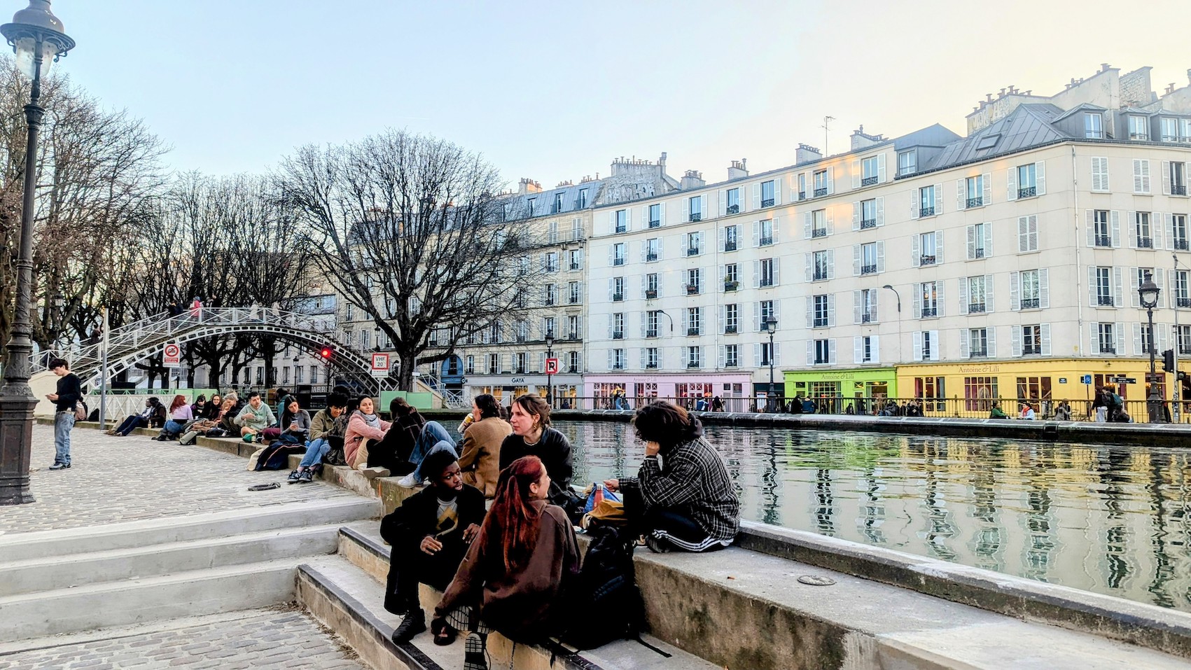 The local youth is hanging out by the Canal Saint Martin on a balmy weekday afternoon.