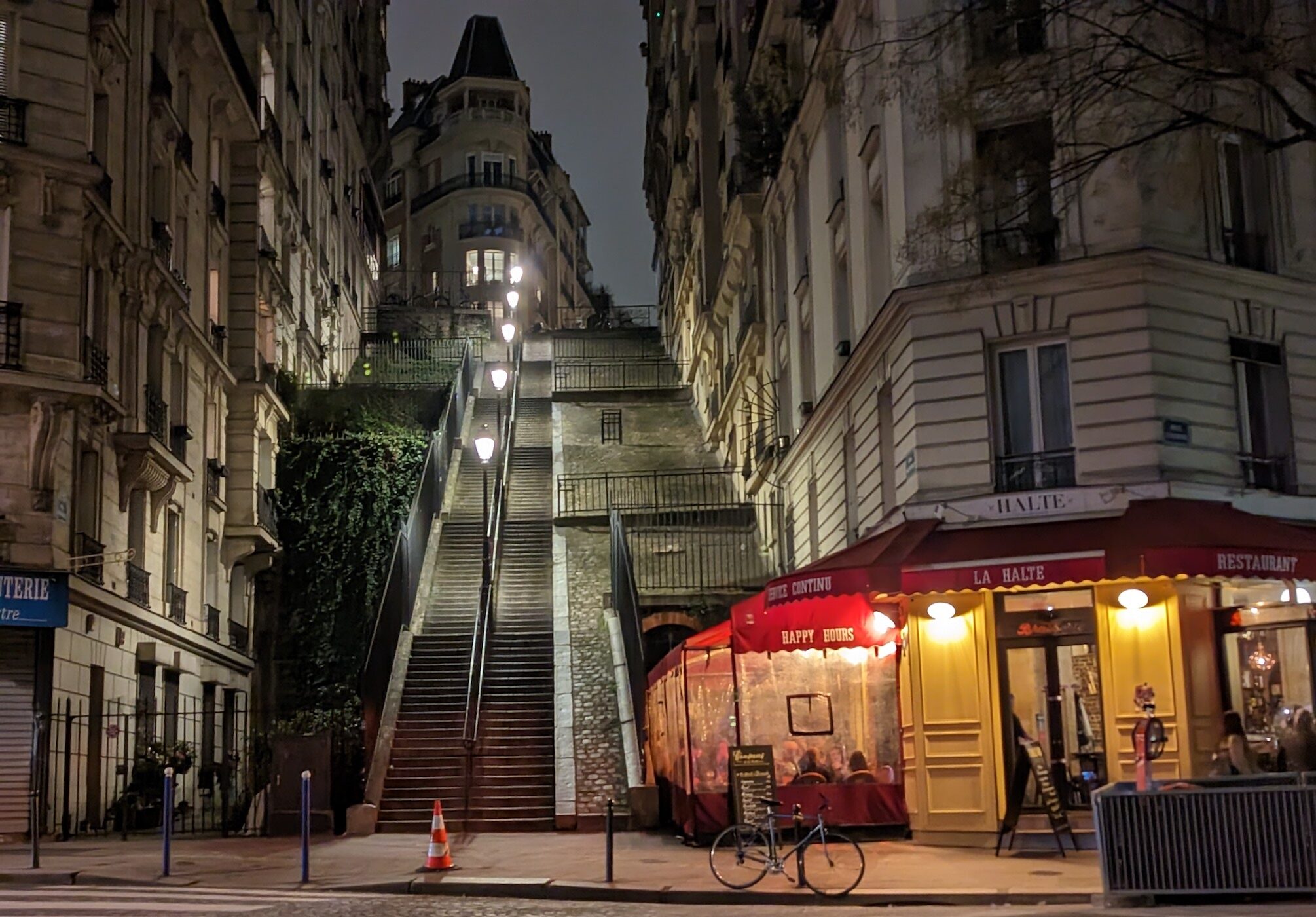 A lit bistro in front of stairs that lead up to Montmartre.