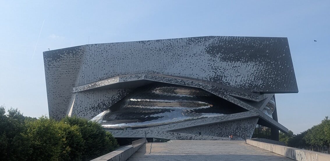 The modern silver building of the Paris Philharmonic seen from the path on the GR75 walk that leads past it.