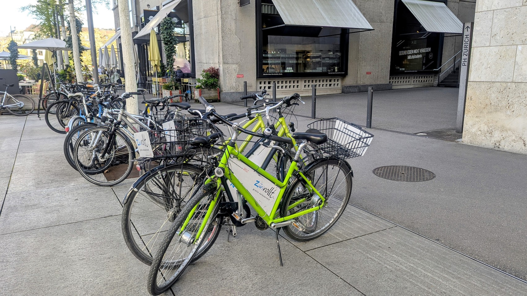 The signature green bikes of Züri Rollt parked in front of the Hiltl Sihlpost next to Zurich's main station.