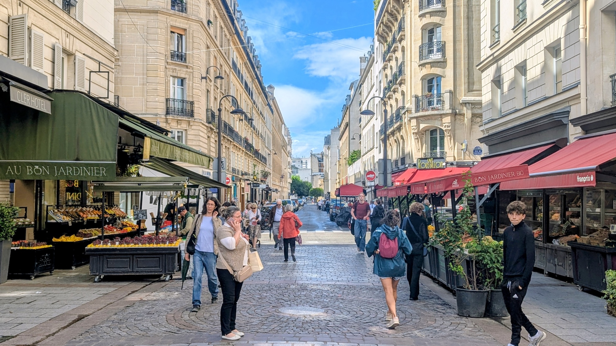 Fruit stands and shoppers on Rue Cler, a lively market street close to the Eiffel Tower.