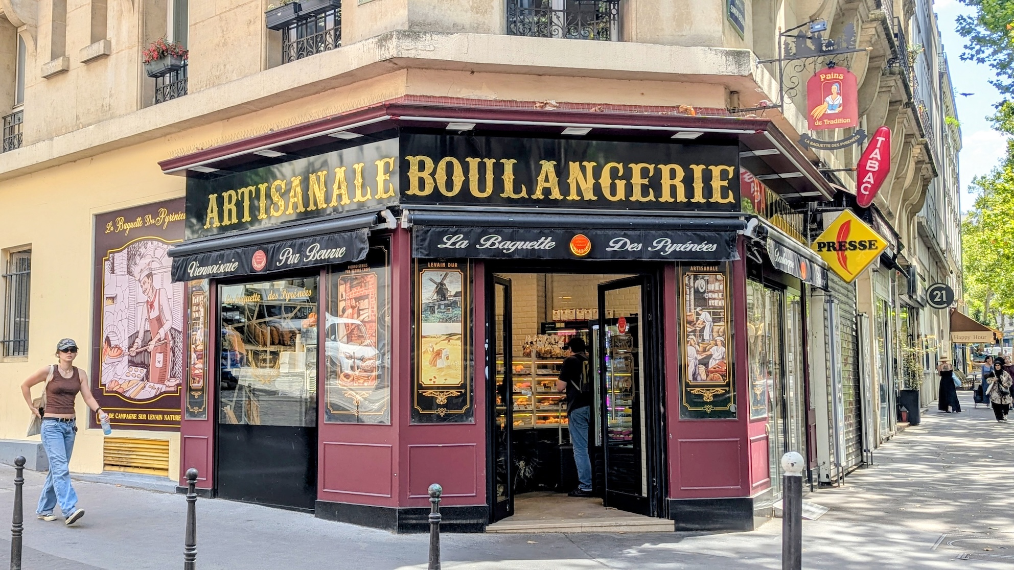 A woman walking past a Parisian bakery with the sign Boulangerie Artisanale on the store front.